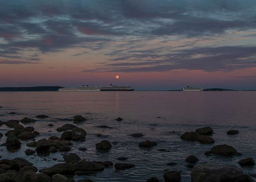 DORCHESTER, Dorset, Sturgeon Moonset over Weymouth Bay with mothballed cruise liners....