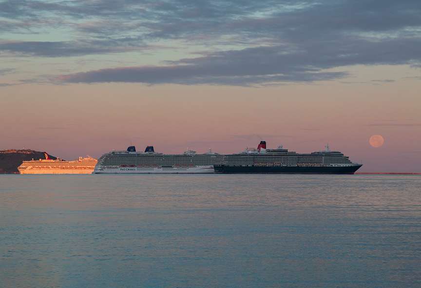 DORCHESTER, Dorset, Sunrise and Sturgeon Moonset over Weymouth Bay with mothballed cruise liner...