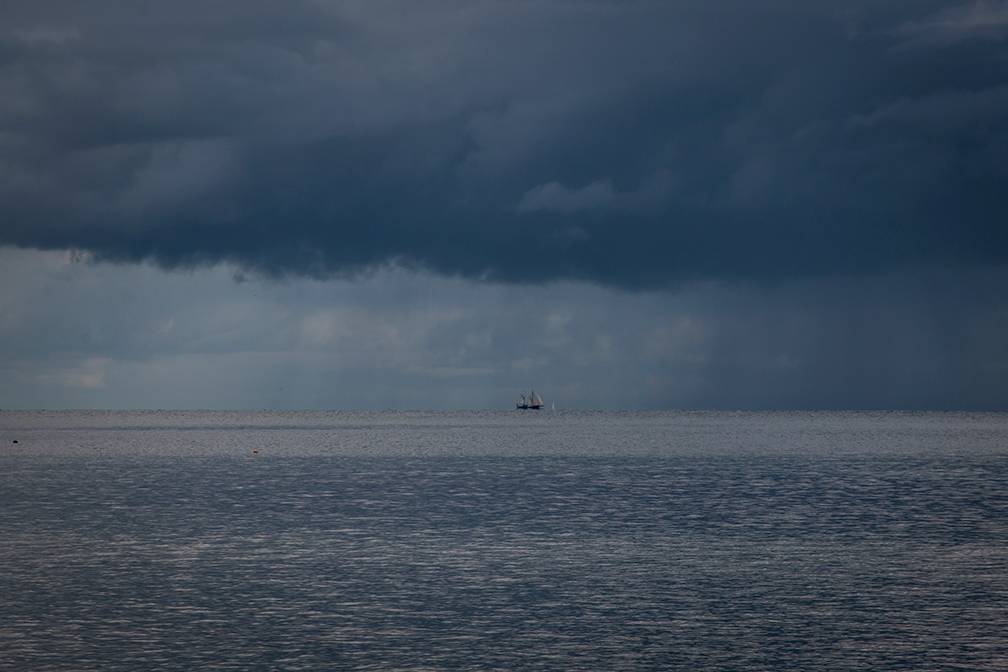 Weymouth, Dorset, Rain shower over English Channel with small sailing boat....