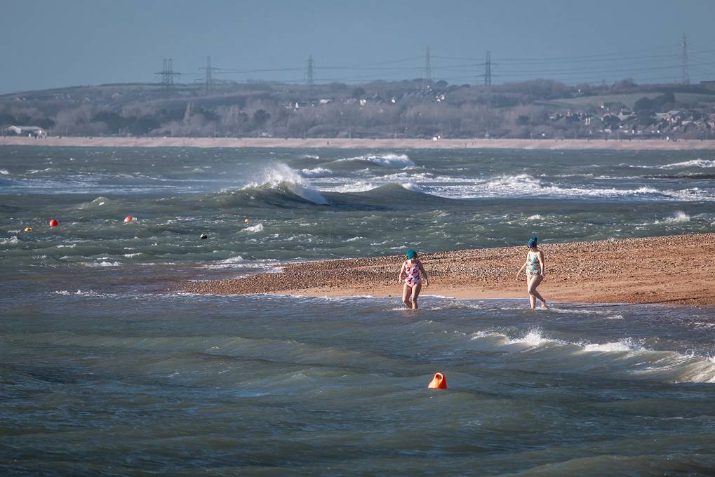 Weymouth, Dorset, After Storm Bella – Two swimmers go for a dip in Ringstead Bay at the end o...